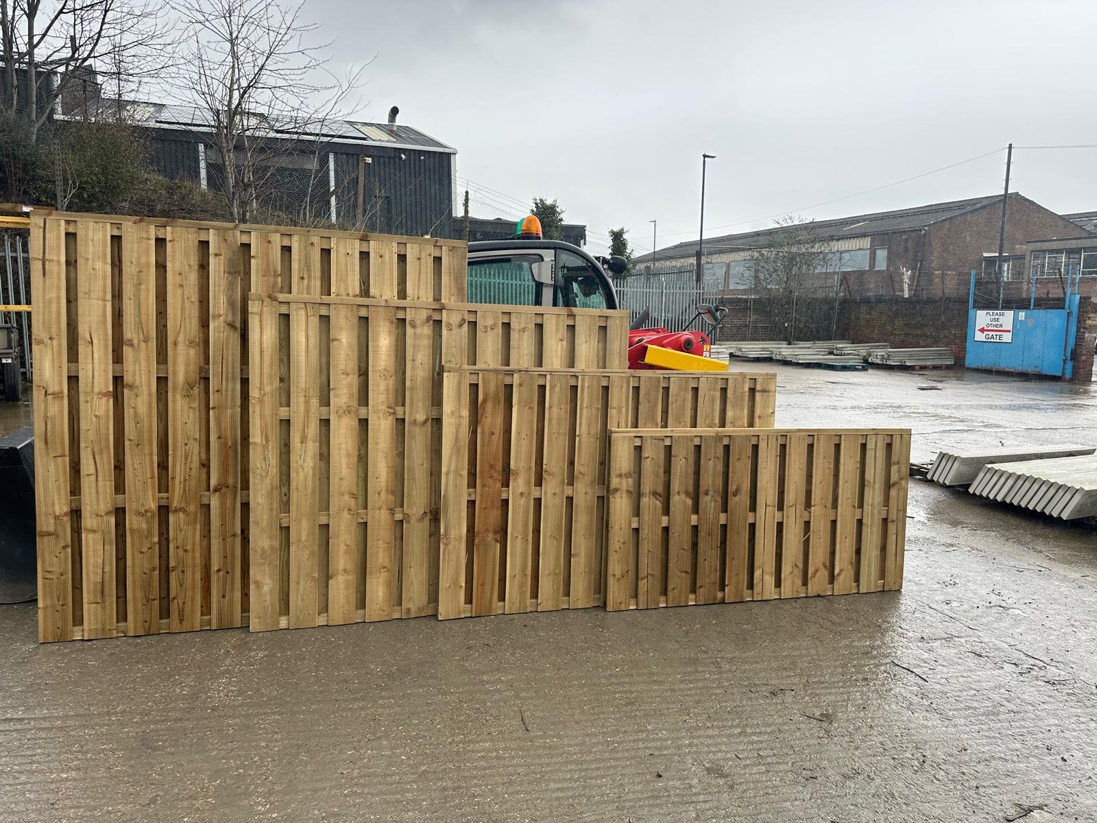 Wooden pallet fence partially submerged in flood water at an industrial yard